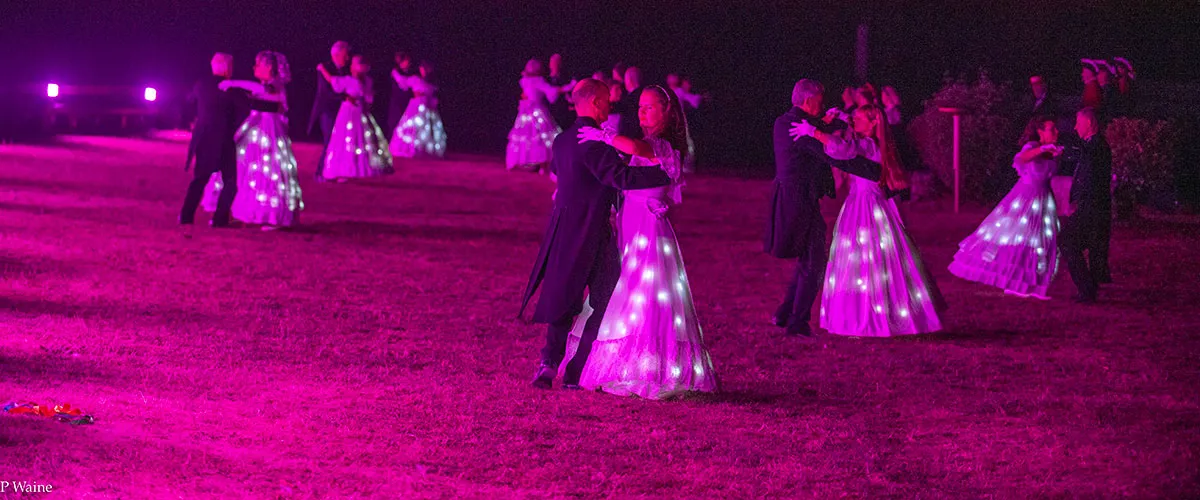 Des danseurs dans les lumières roses du spectacle.